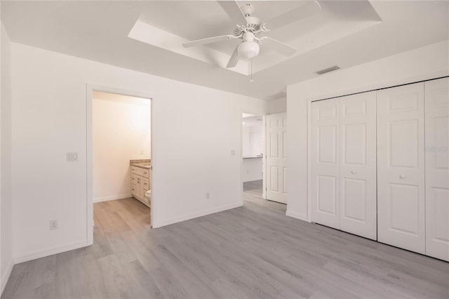 unfurnished bedroom featuring ceiling fan, light hardwood / wood-style floors, connected bathroom, and a closet