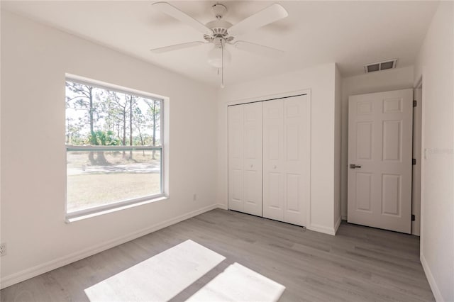 unfurnished bedroom featuring light hardwood / wood-style floors, a closet, and ceiling fan