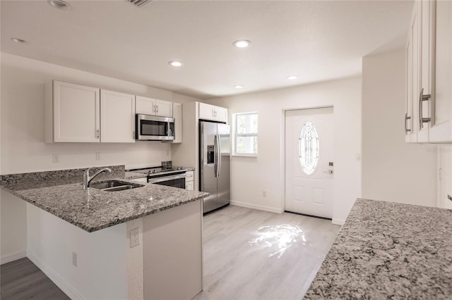 kitchen featuring stone counters, sink, stainless steel appliances, light hardwood / wood-style flooring, and white cabinets