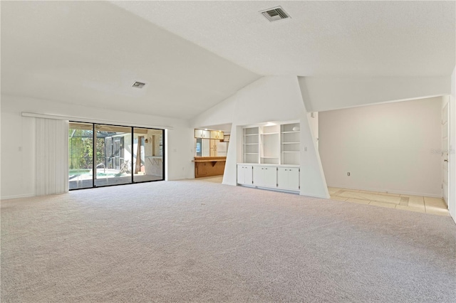 unfurnished living room with light colored carpet and vaulted ceiling