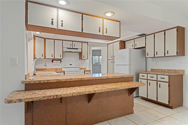 kitchen featuring white appliances, white cabinets, a kitchen breakfast bar, sink, and light tile patterned floors