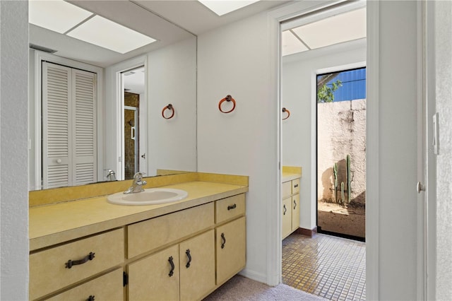 bathroom featuring tile patterned flooring, vanity, and a skylight