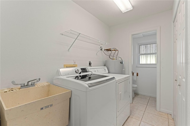 washroom featuring electric water heater, light tile patterned flooring, independent washer and dryer, and sink