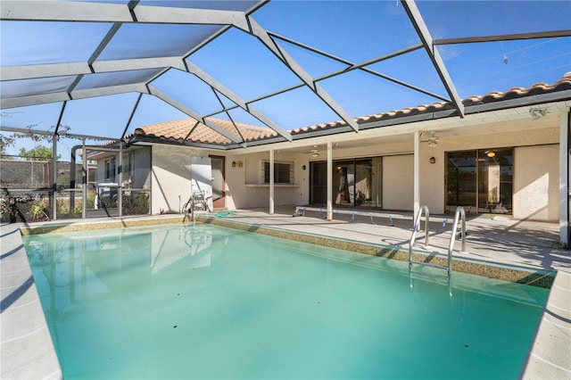 view of swimming pool featuring glass enclosure, ceiling fan, and a patio