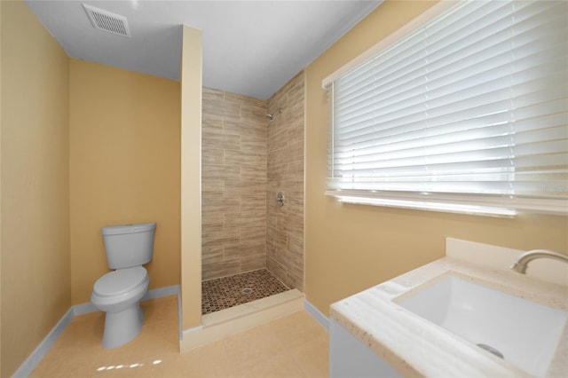 bathroom featuring tiled shower, tile patterned floors, vanity, and toilet