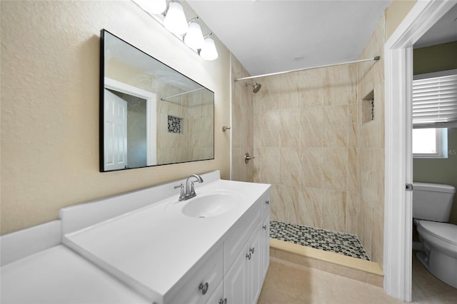 bathroom featuring tiled shower, tile patterned flooring, vanity, and toilet