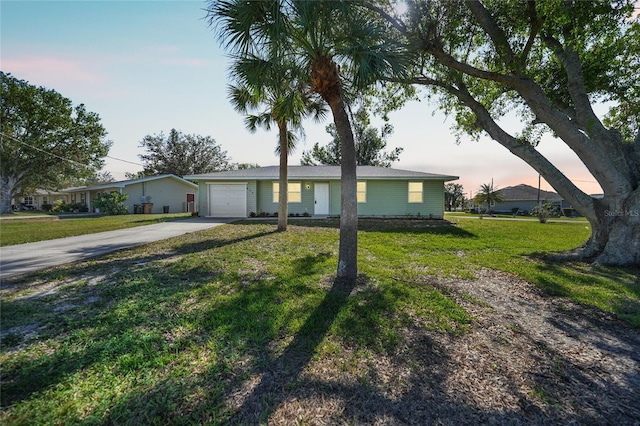 single story home featuring a garage and a lawn