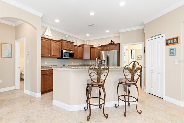 kitchen with ornamental molding, stainless steel appliances, light stone counters, and a center island with sink