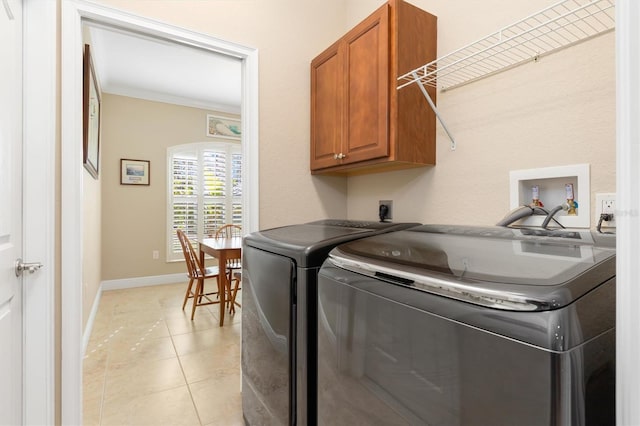 laundry area with washing machine and dryer, light tile patterned floors, cabinets, and ornamental molding