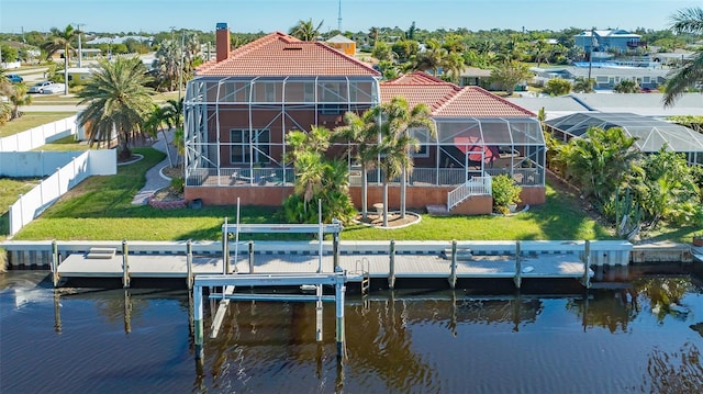 back of property with a yard, a water view, and glass enclosure