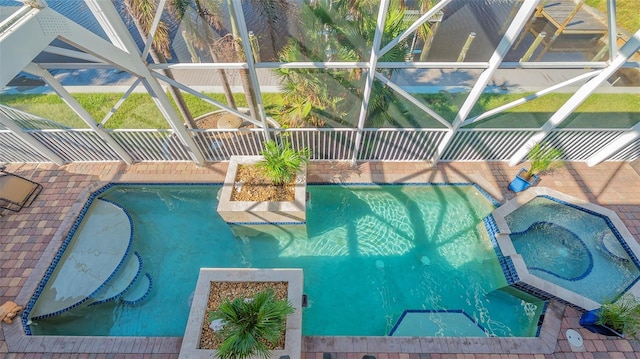 view of swimming pool featuring glass enclosure and an in ground hot tub