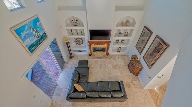 living room with built in shelves, a high ceiling, and a wealth of natural light