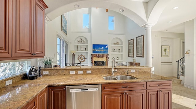 kitchen featuring built in shelves, light stone counters, sink, and stainless steel dishwasher