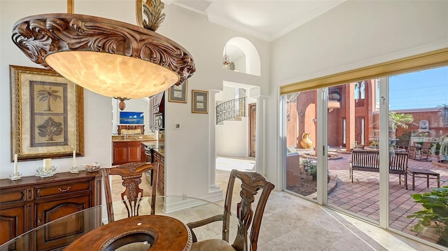 dining room with a towering ceiling, ornate columns, and crown molding