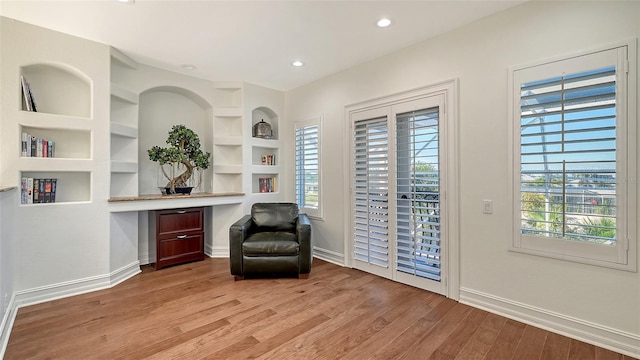 unfurnished room featuring a wealth of natural light, built in features, built in desk, and light wood-type flooring