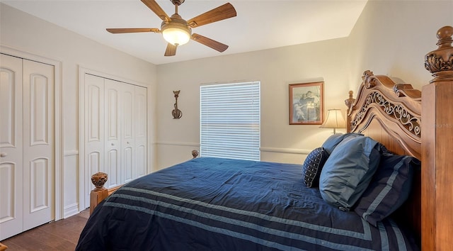 bedroom with two closets, ceiling fan, and dark wood-type flooring