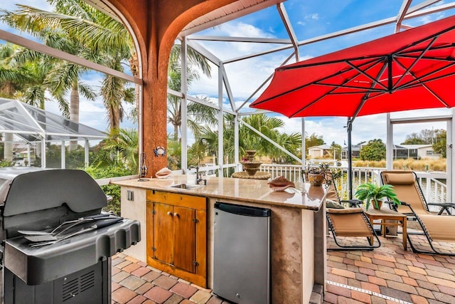 view of patio featuring area for grilling, glass enclosure, and a wet bar