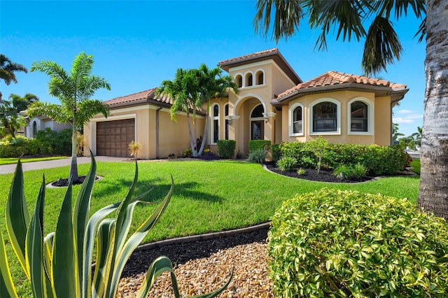 mediterranean / spanish home featuring a garage and a front lawn