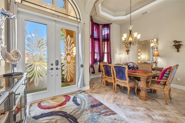 dining room with a raised ceiling, french doors, and a chandelier