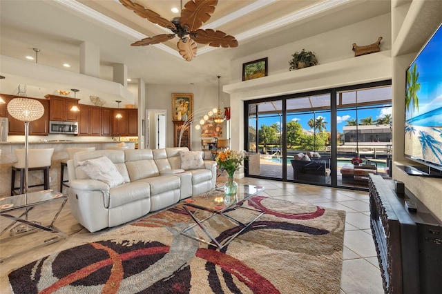 tiled living room with crown molding, a towering ceiling, and ceiling fan with notable chandelier