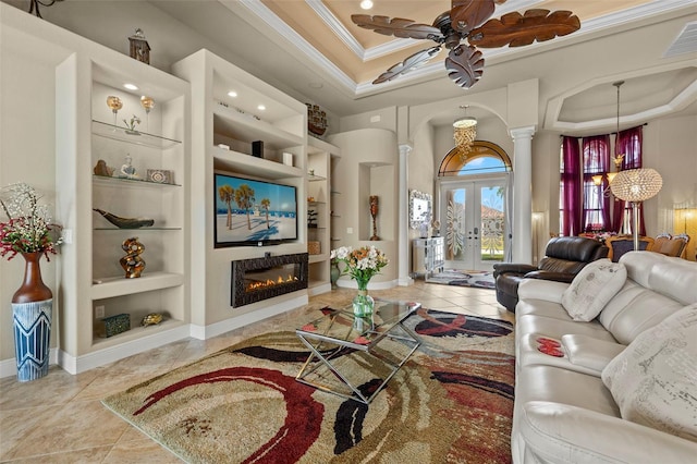 living room with french doors, ornamental molding, a tray ceiling, ceiling fan, and built in features