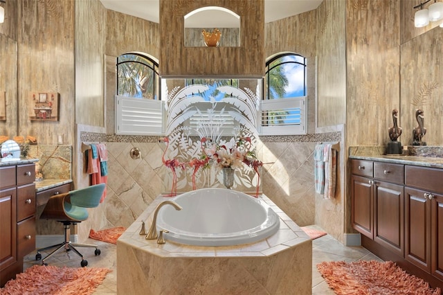 bathroom with tile patterned floors, vanity, tile walls, and tiled bath