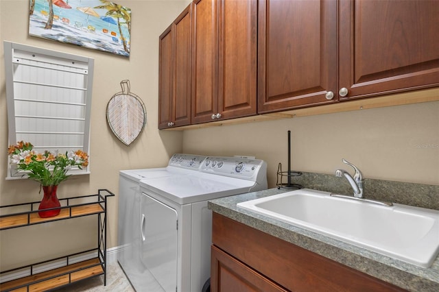 clothes washing area with cabinets, washer and clothes dryer, and sink