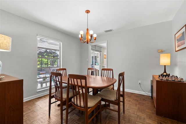 dining area featuring a chandelier and dark parquet flooring