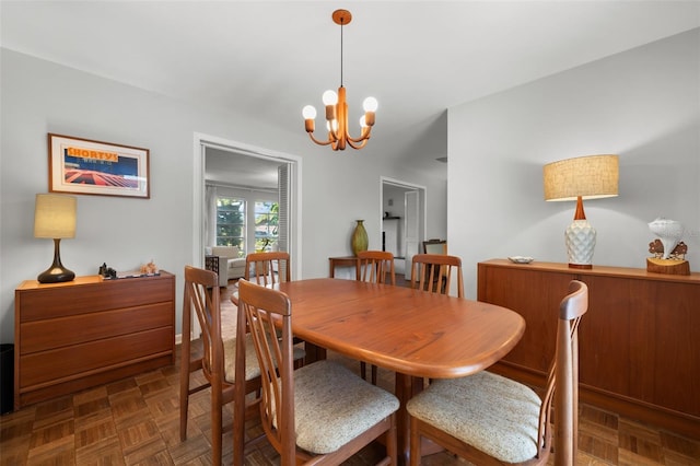 dining room featuring dark parquet flooring and an inviting chandelier