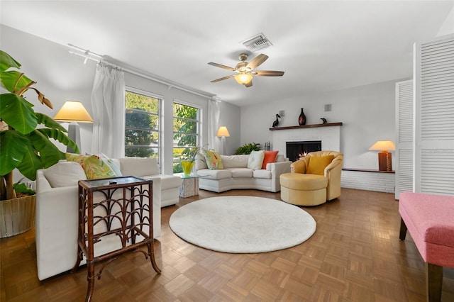 living room featuring dark parquet floors, a brick fireplace, and ceiling fan