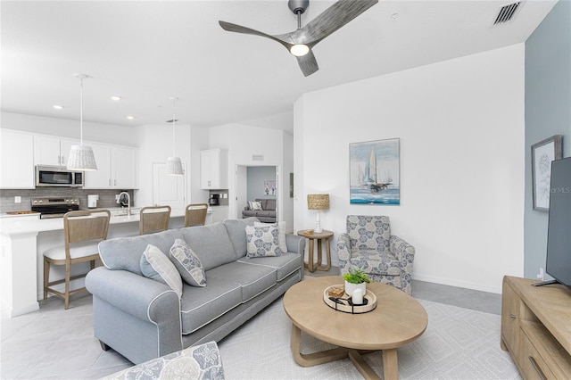 tiled living room with ceiling fan and sink