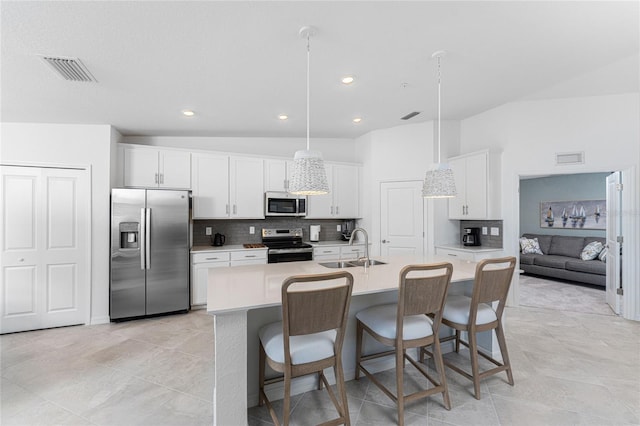 kitchen with pendant lighting, sink, stainless steel appliances, and a kitchen island with sink