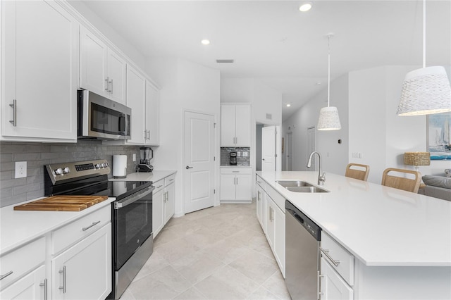 kitchen featuring decorative backsplash, stainless steel appliances, a kitchen island with sink, sink, and hanging light fixtures