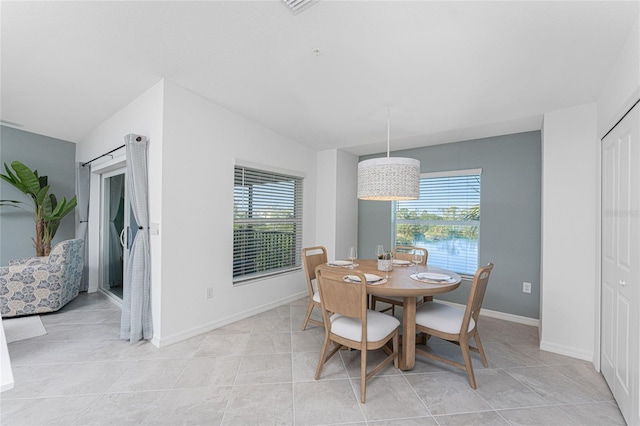 dining room with light tile patterned floors, a water view, a wealth of natural light, and lofted ceiling