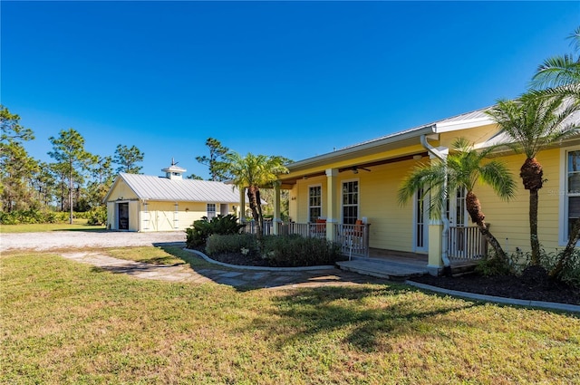 view of front of house with a garage, covered porch, an outdoor structure, and a front yard