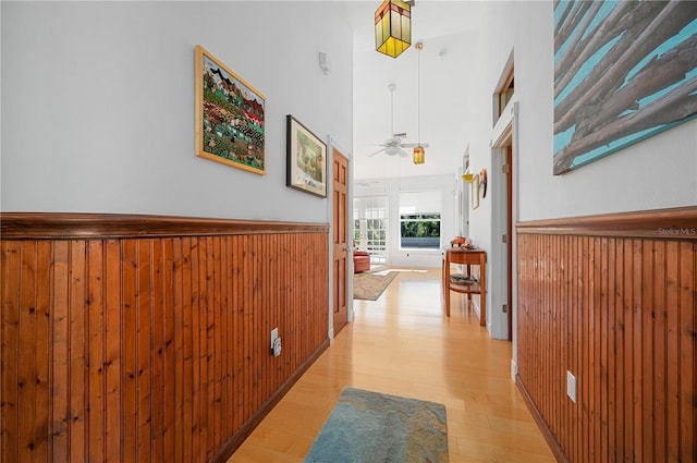 hallway with light hardwood / wood-style floors and a towering ceiling