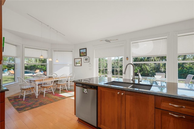 kitchen with dishwasher, sink, dark stone countertops, a wealth of natural light, and light hardwood / wood-style floors