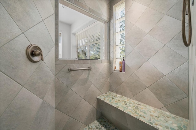 bathroom with a tile shower and plenty of natural light