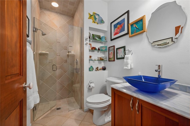 bathroom featuring tile patterned flooring, vanity, toilet, and a shower with shower door