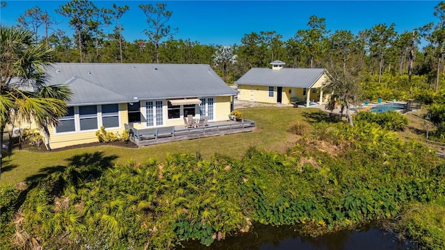 rear view of house featuring a lawn and a deck with water view