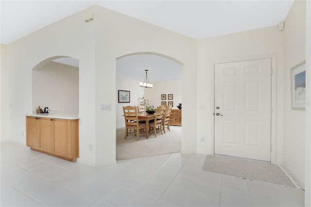 carpeted entryway featuring sink and an inviting chandelier