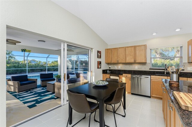 kitchen featuring dishwasher, sink, vaulted ceiling, decorative backsplash, and light tile patterned flooring