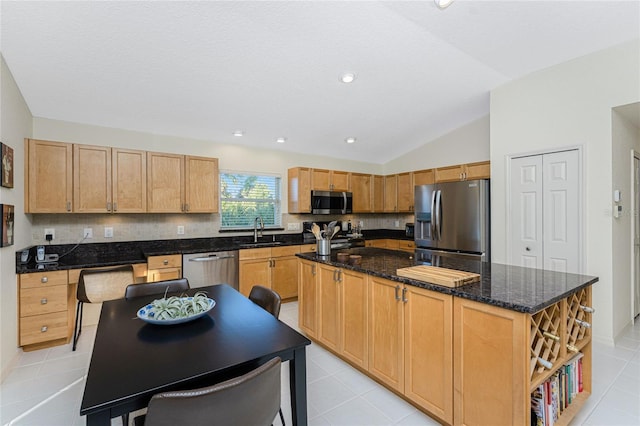 kitchen featuring sink, vaulted ceiling, light tile patterned floors, a kitchen island, and stainless steel appliances