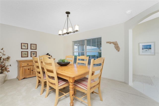 carpeted dining area with a chandelier