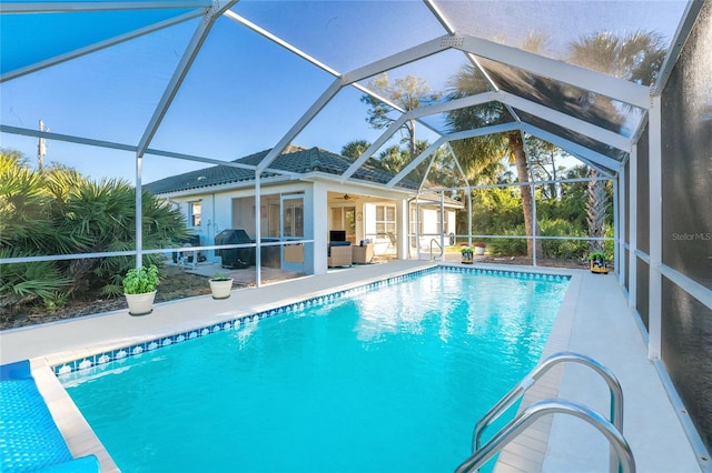 view of swimming pool featuring a patio area, ceiling fan, and glass enclosure