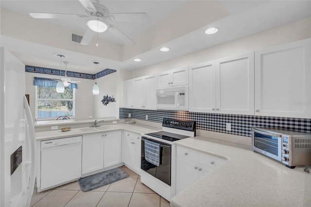 kitchen featuring white appliances, decorative light fixtures, white cabinetry, and a tray ceiling