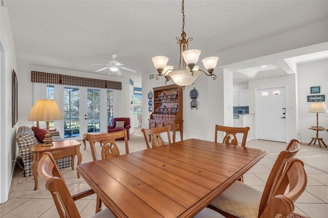 tiled dining area with french doors and ceiling fan with notable chandelier