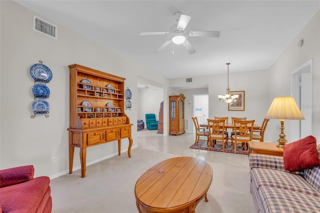 tiled living room with ceiling fan with notable chandelier