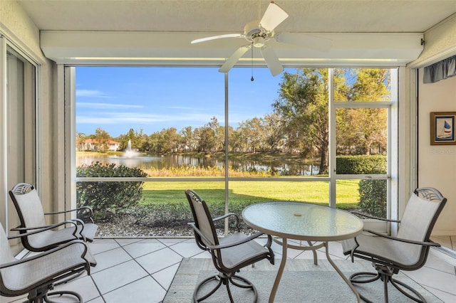 sunroom with ceiling fan and a water view