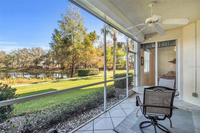 sunroom with ceiling fan and a water view